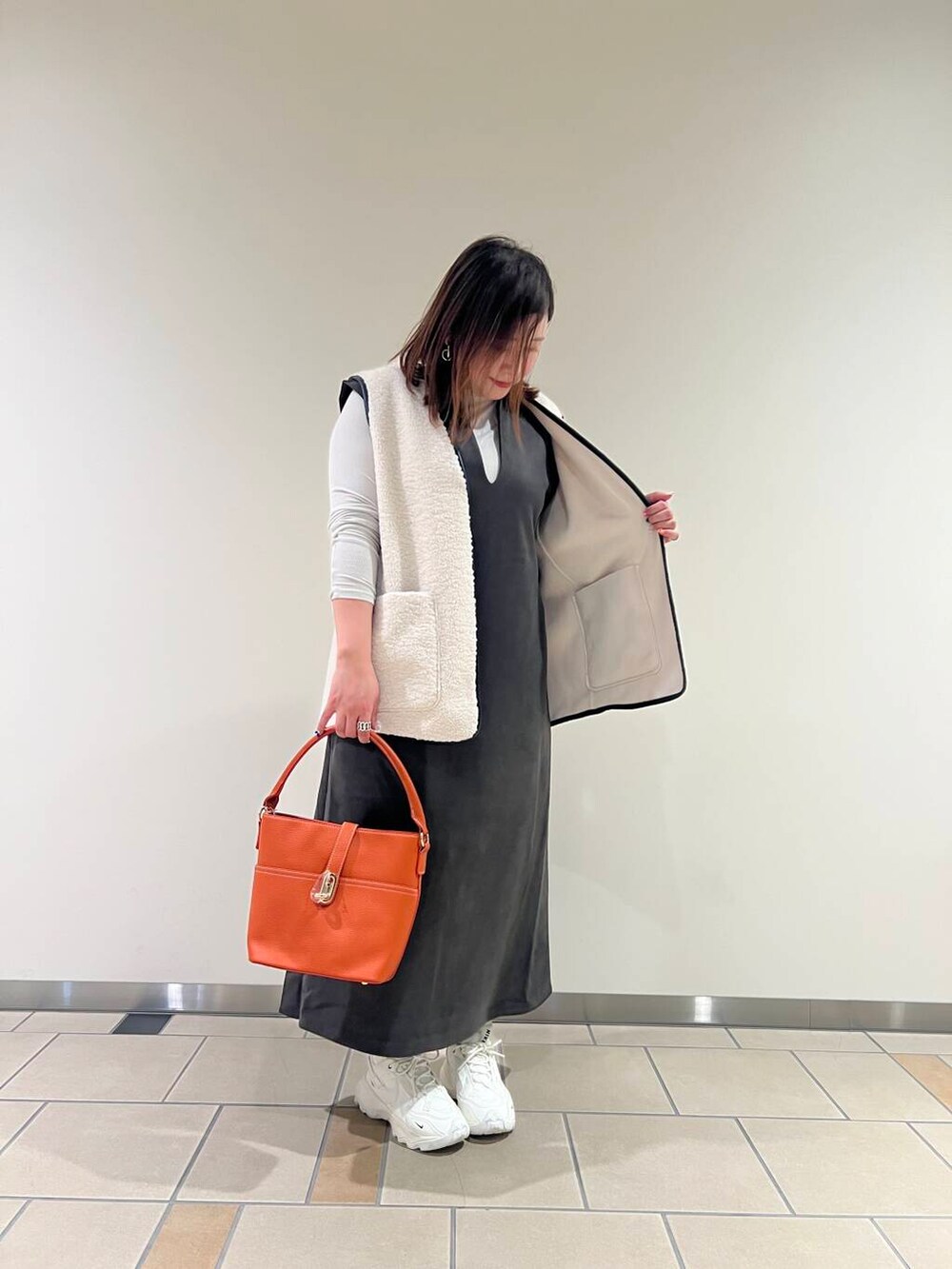 グレー系のTシャツ/カットソー、オレンジ系のハンドバッグ、ホワイト系のその他アウターを着用したレディースの秋コーディネートの2枚目の写真