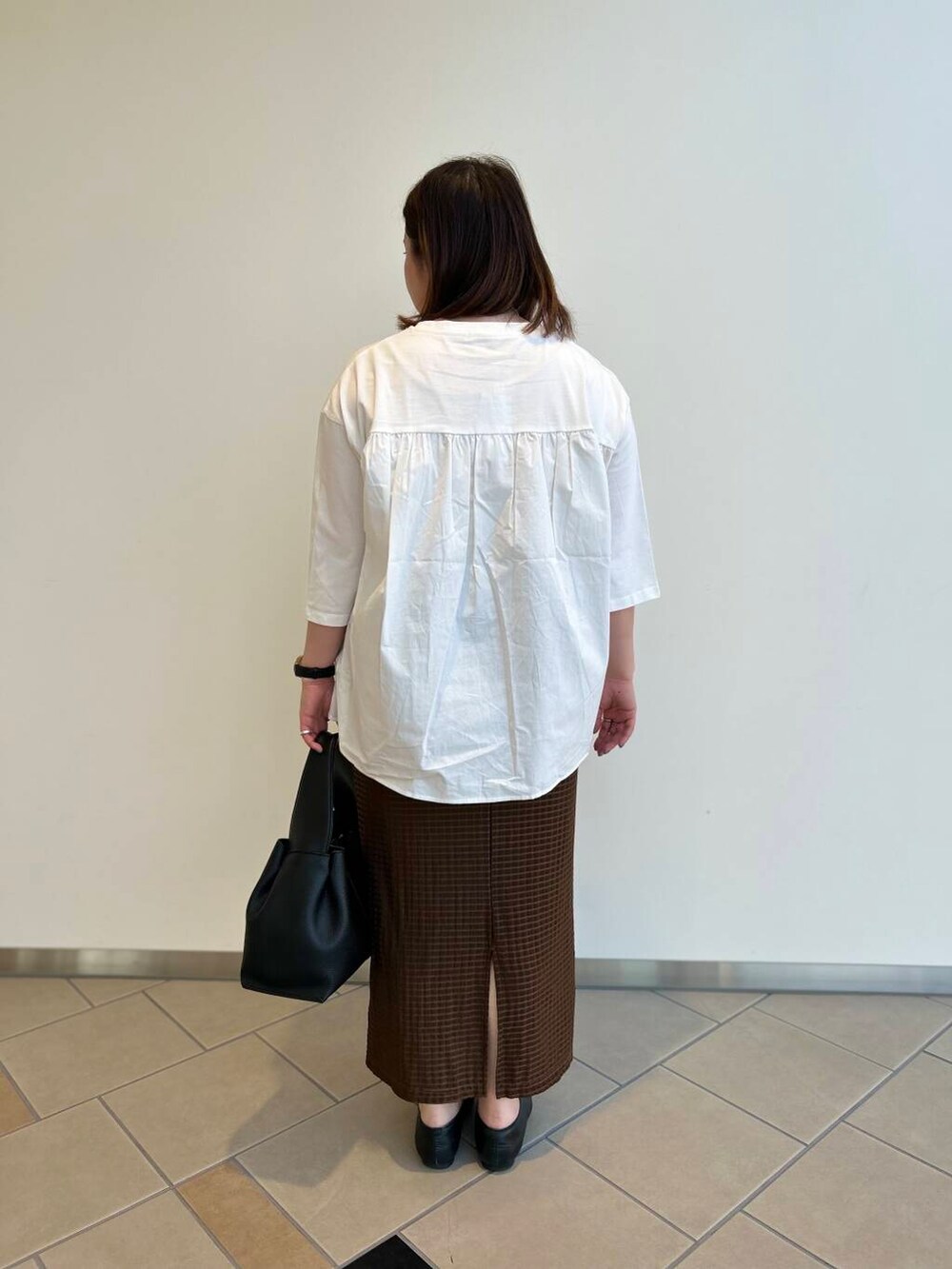 ブラック系のハンドバッグ、ホワイト系のTシャツ/カットソー、ブラウン系のスカートを着用したレディースの夏コーディネートの3枚目の写真