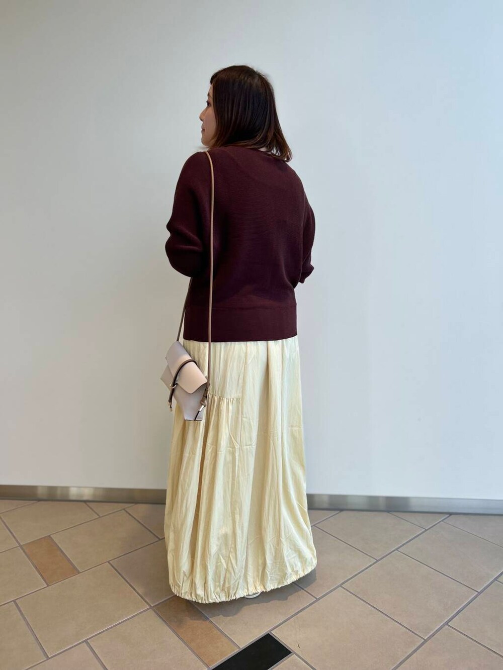 ホワイト系のショルダーバッグ、ブラウン系のニット/セーター、イエロー系のスカートを着用したレディースの夏コーディネートの2枚目の写真