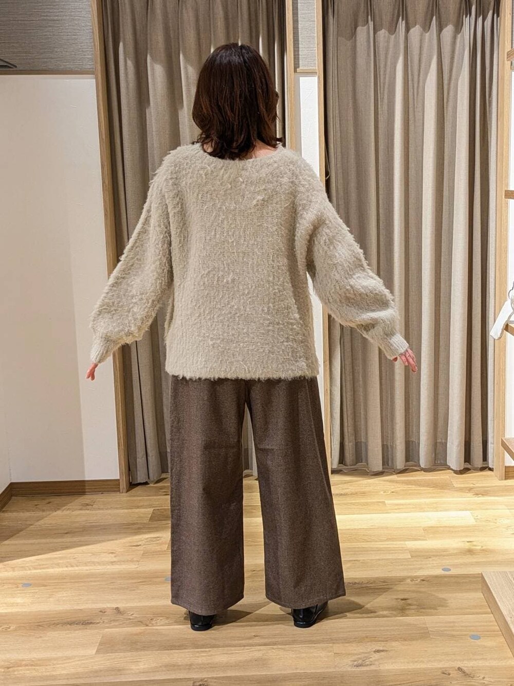 ブラウン系のその他パンツ、ベージュ系のニット/セーター、ブラック系のトートバッグを着用したレディースの冬コーディネートの3枚目の写真