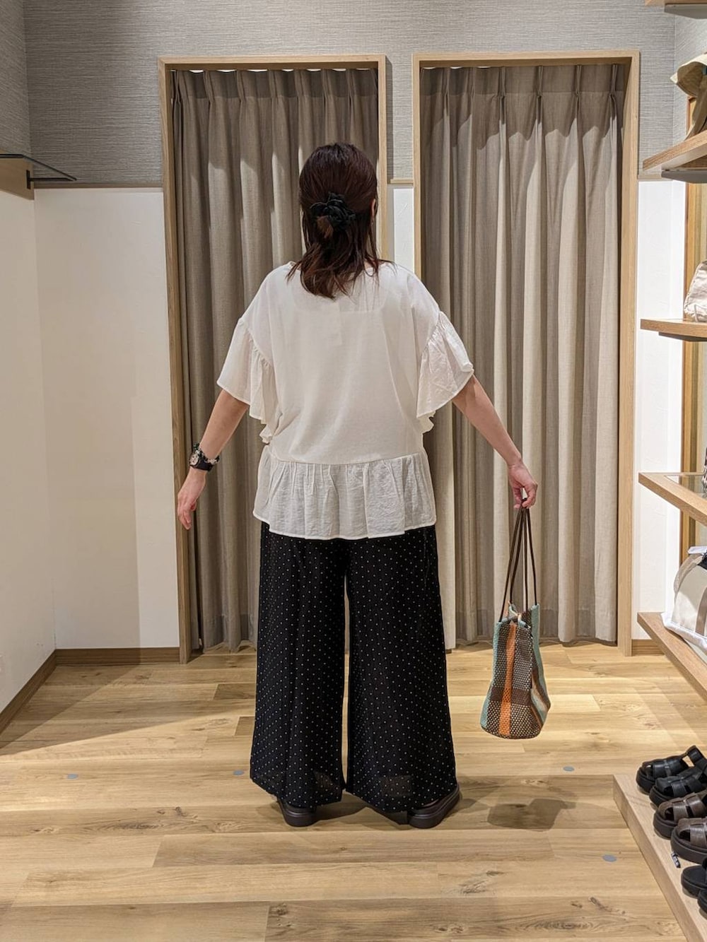 ブラウン系のトートバッグ、ブラウン系のサンダル、ブラック系のその他パンツを着用したレディースの夏コーディネートの2枚目の写真