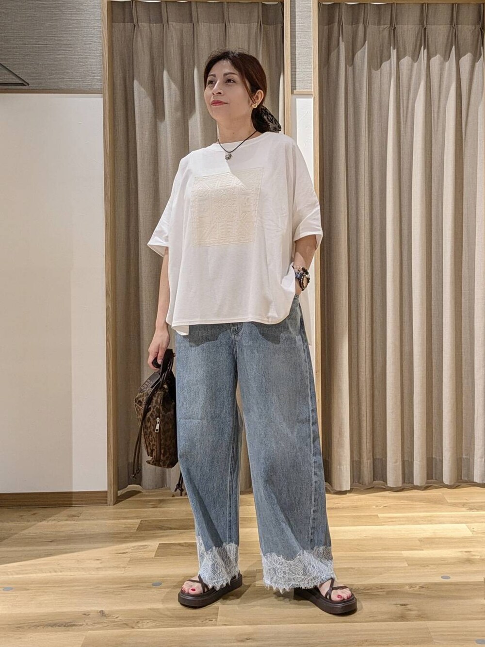 ブルー系のデニムパンツ、ブラウン系のサンダル、その他のTシャツ/カットソーを着用したレディースの夏コーディネートの4枚目の写真