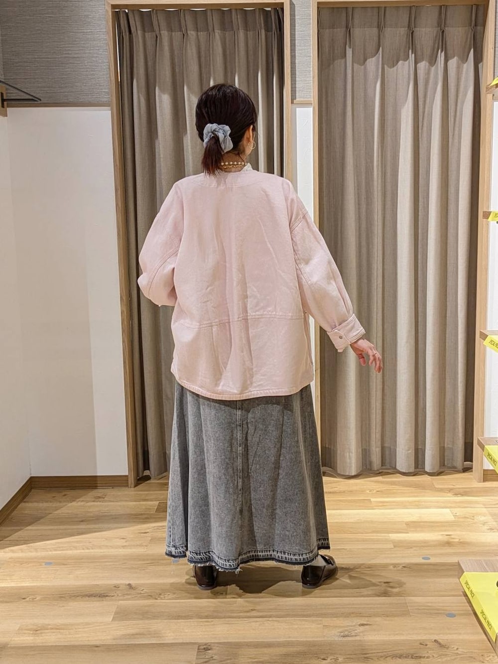 グレー系のデニムスカート、ピンク系のノーカラージャケット、ブラウン系のショルダーバッグを着用したレディースの冬コーディネートの2枚目の写真