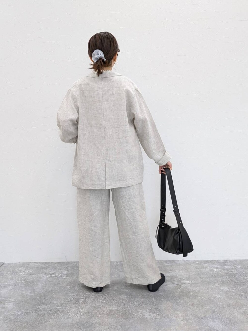 ブラック系のショルダーバッグ、グレー系のパンプス、グレー系のシュシュを着用したレディースの春コーディネートの2枚目の写真