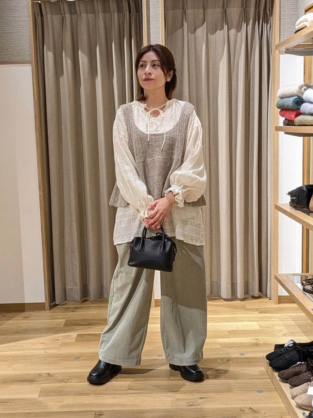 ブラック系のブーツ、ベージュ系のベスト、ホワイト系のシャツ/ブラウスを着用したレディースの冬コーディネートの2枚目の写真