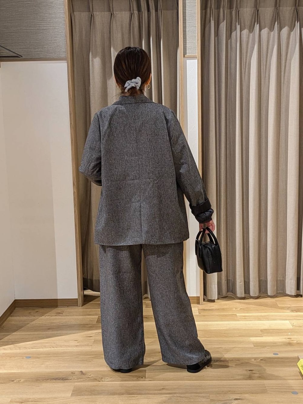 グレー系のスラックス、ブラック系のスニーカー、ブラック系のトートバッグを着用したレディースの冬コーディネートの2枚目の写真