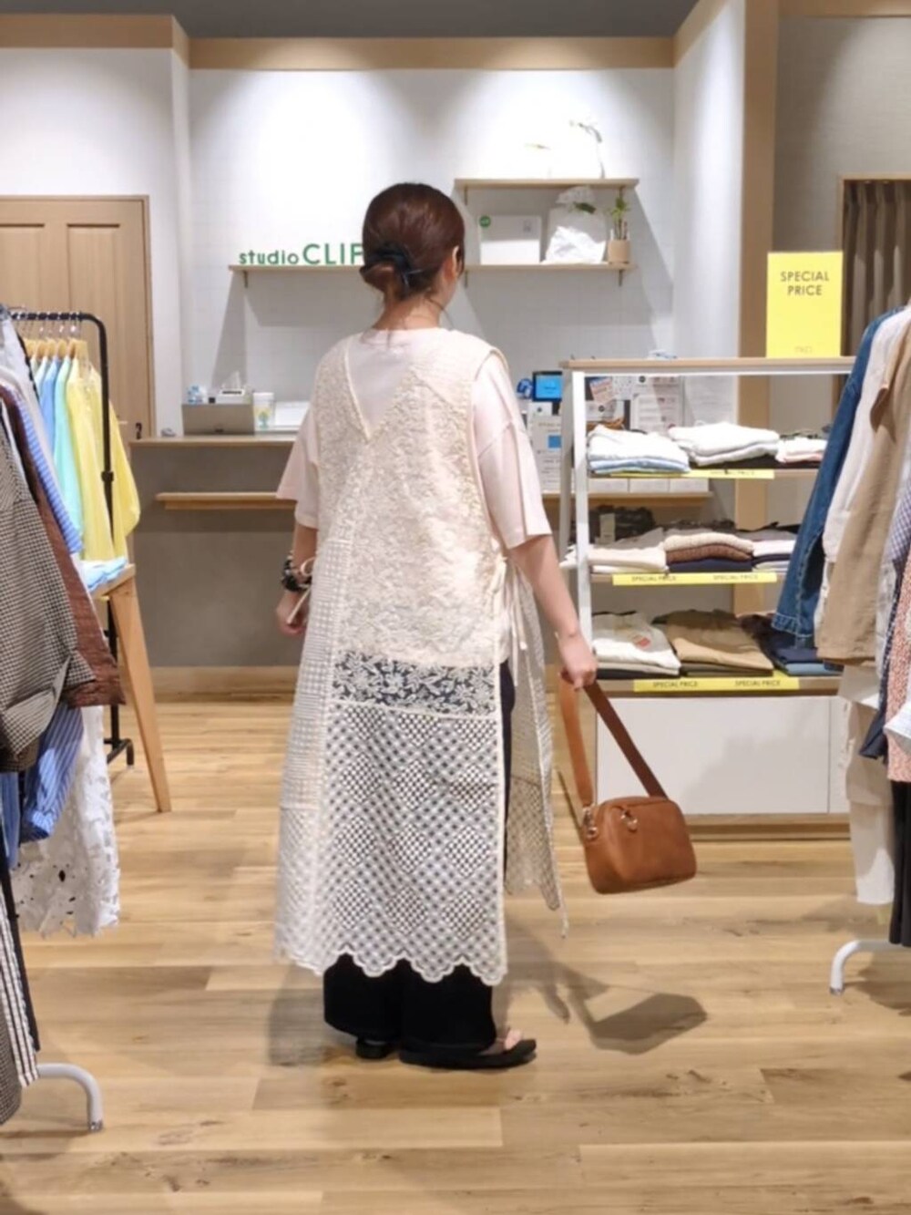 ブラウン系のショルダーバッグ、ゴールド系のサンダル、ブルー系のデニムパンツを着用したレディースの夏コーディネートの2枚目の写真