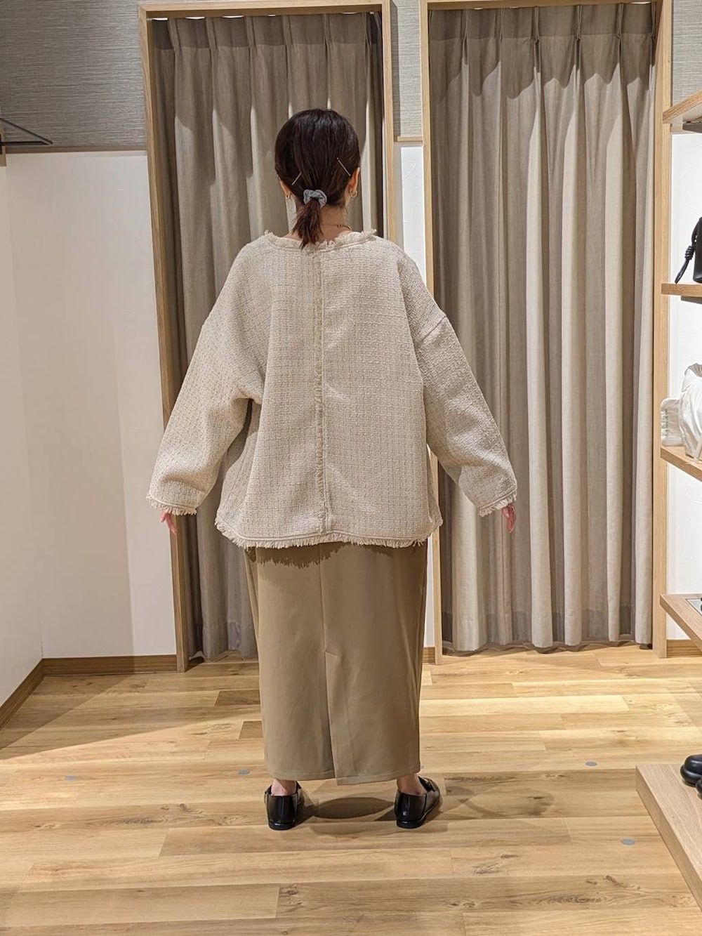 ベージュ系のノーカラージャケット、ベージュ系のスカート、ブラック系のトートバッグを着用したレディースの冬コーディネートの2枚目の写真