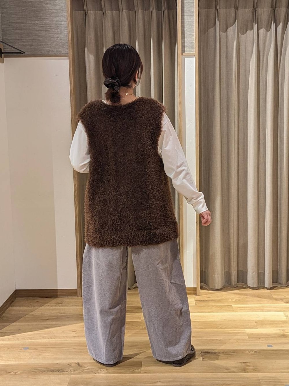 ブラウン系のベスト、グレー系のその他パンツ、ブラウン系のショルダーバッグを着用したレディースの冬コーディネートの2枚目の写真