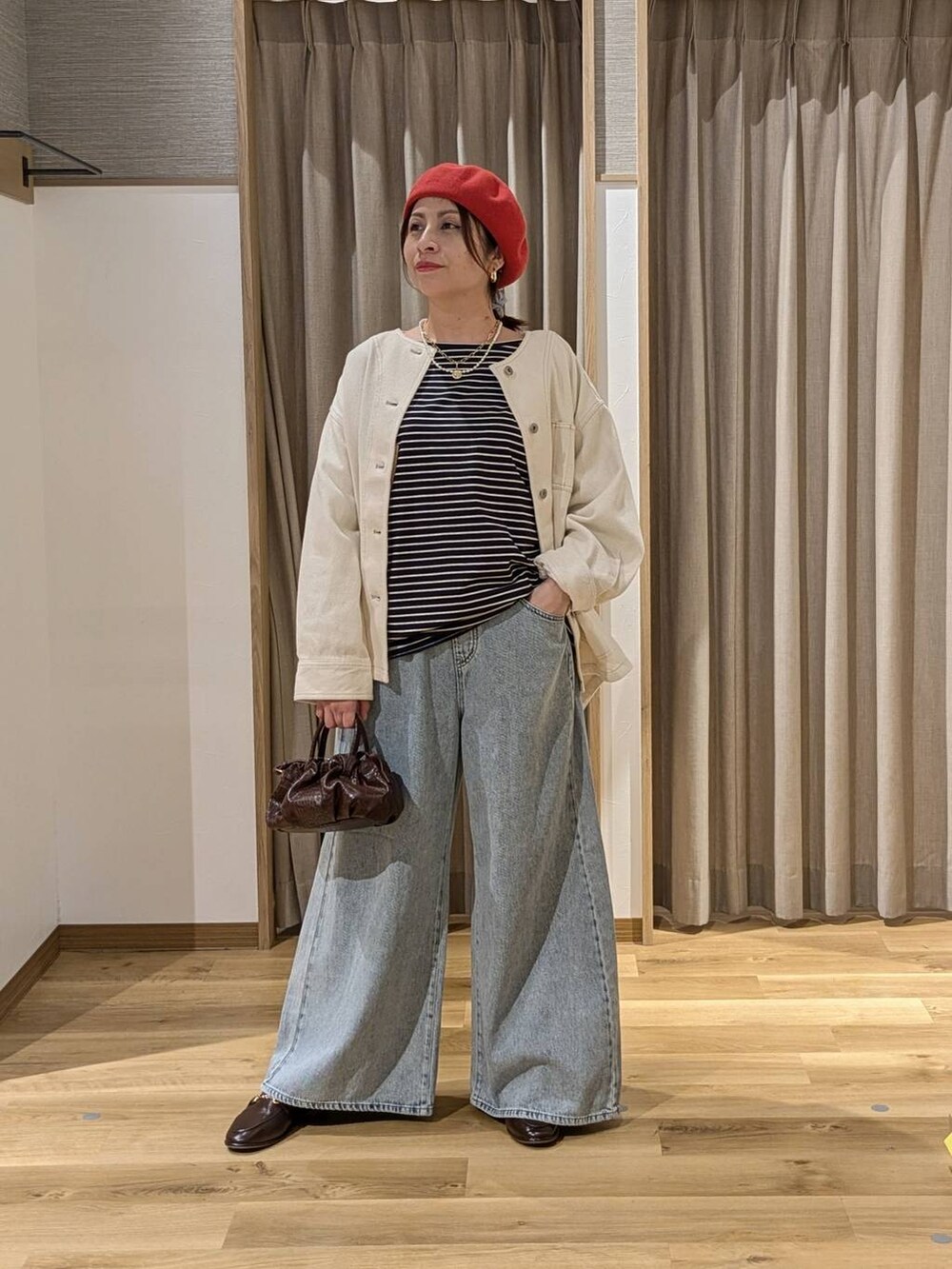 ブルー系のデニムパンツ、ベージュ系のノーカラージャケット、ブラウン系のショルダーバッグを着用したレディースの冬コーディネートの2枚目の写真