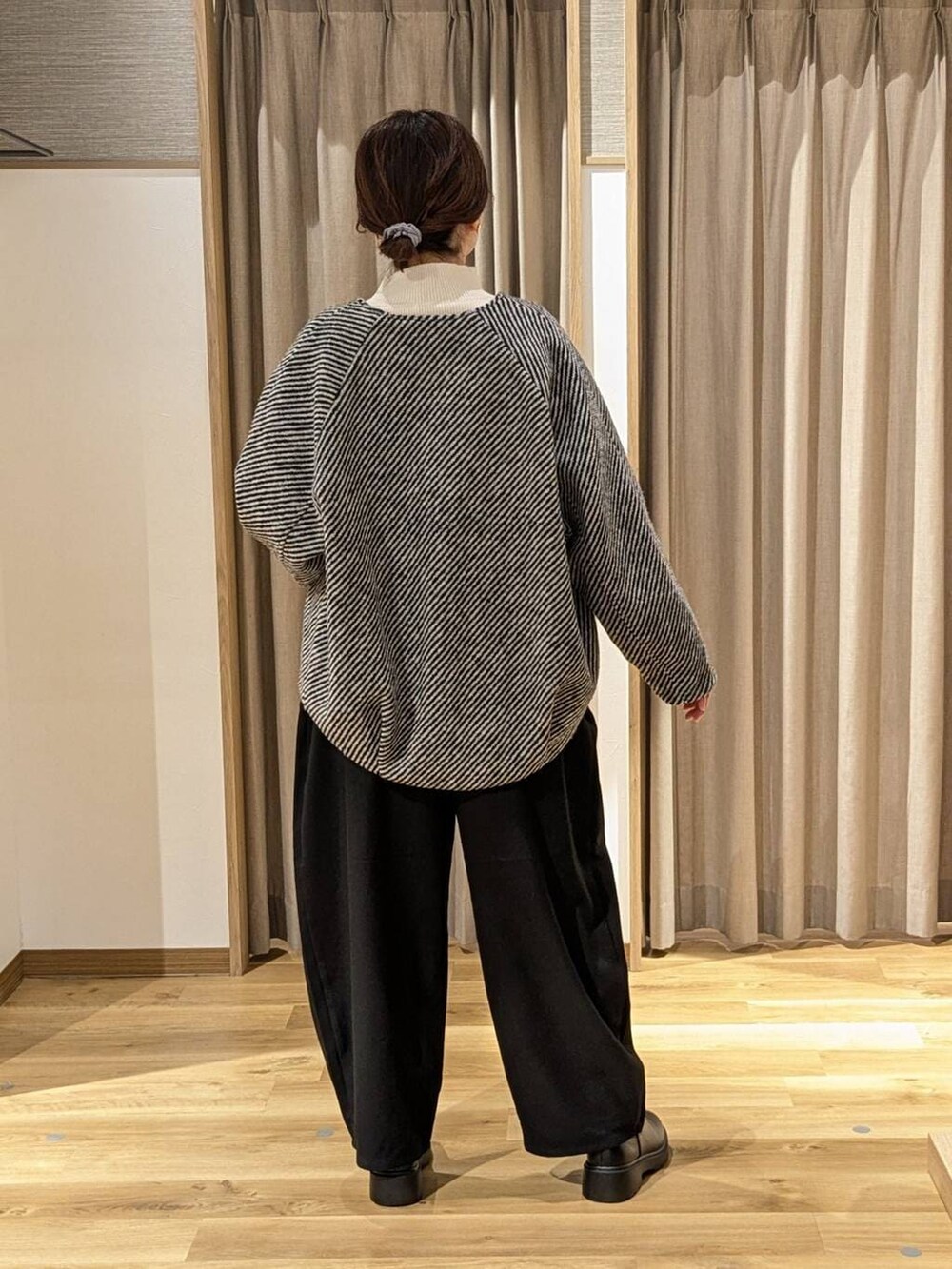 ブラック系のノーカラーコート、ベージュ系のニット/セーター、ブラック系のその他パンツを着用したレディースの冬コーディネートの2枚目の写真