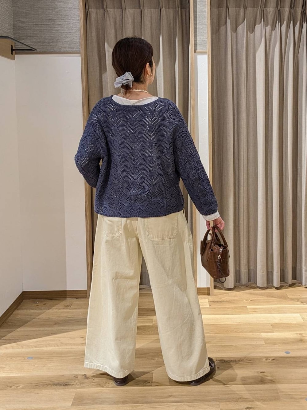 イエロー系のチノパンツ、ブラウン系のトートバッグ、ブラウン系のローファーを着用したレディースの冬コーディネートの2枚目の写真