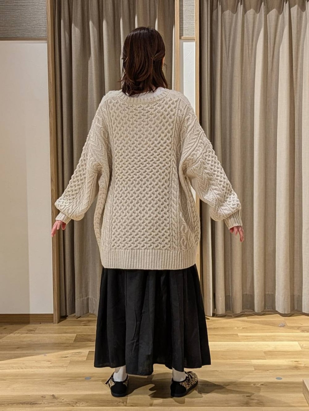 ブラウン系のショルダーバッグ、ブラック系のスニーカー、ブラック系のスカートを着用したレディースの冬コーディネートの2枚目の写真