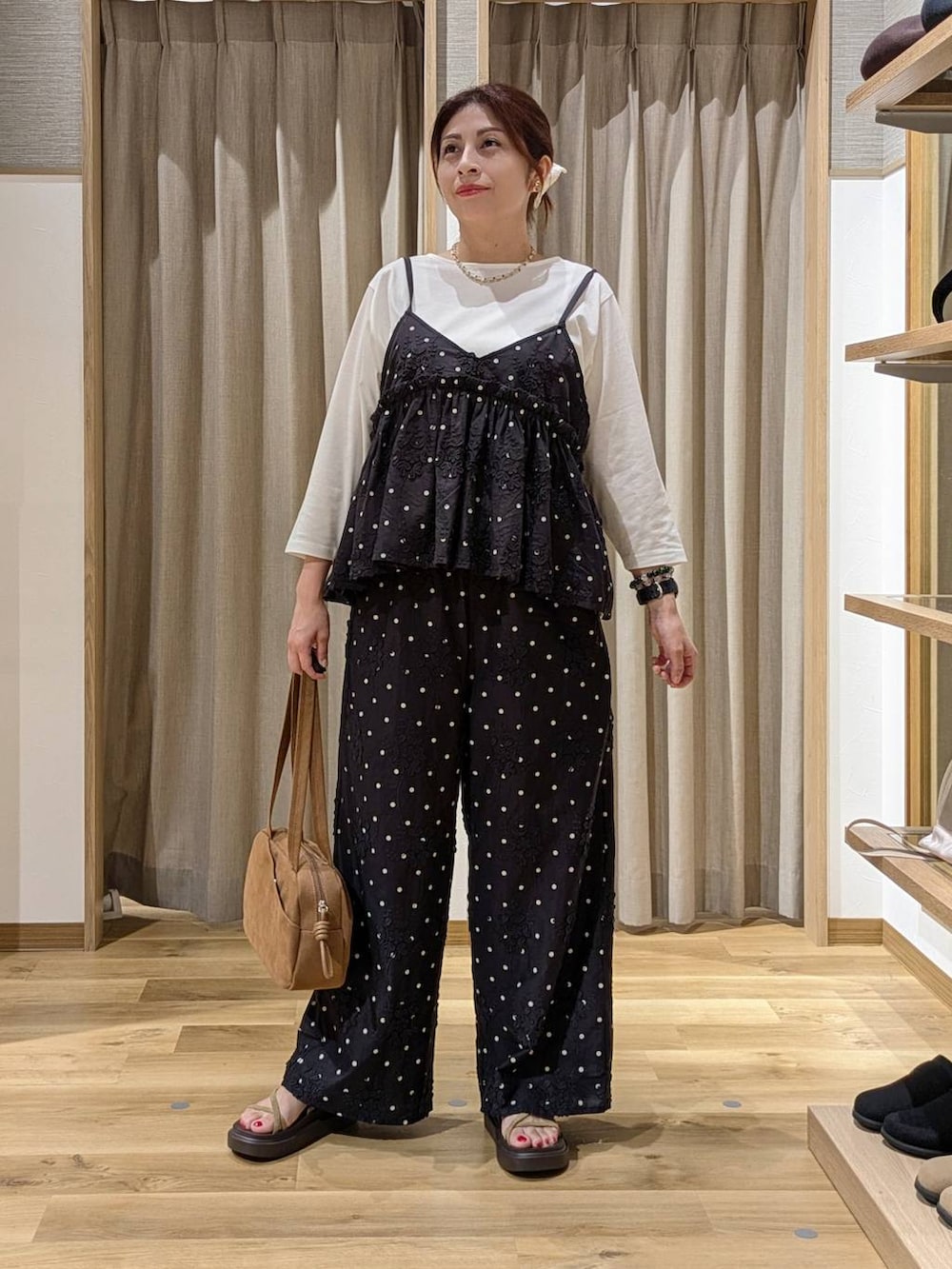 ブラウン系のショルダーバッグ、ブラック系のその他パンツ、ブラック系のキャミソールを着用したレディースの夏コーディネートの2枚目の写真