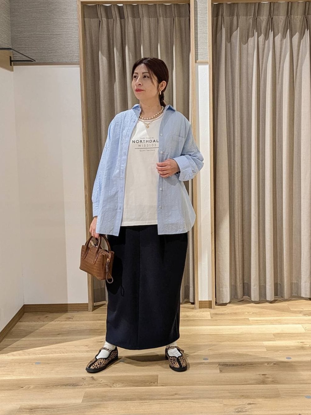 その他のスニーカー、ブルー系のスカート、ブラウン系のトートバッグを着用したレディースの冬コーディネートの2枚目の写真