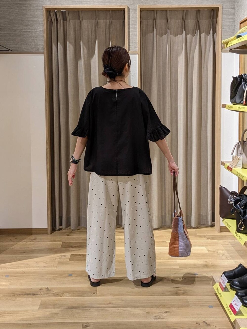 オレンジ系のトートバッグ、ブラック系のサンダル、ブラック系のシャツ/ブラウスを着用したレディースの夏コーディネートの2枚目の写真