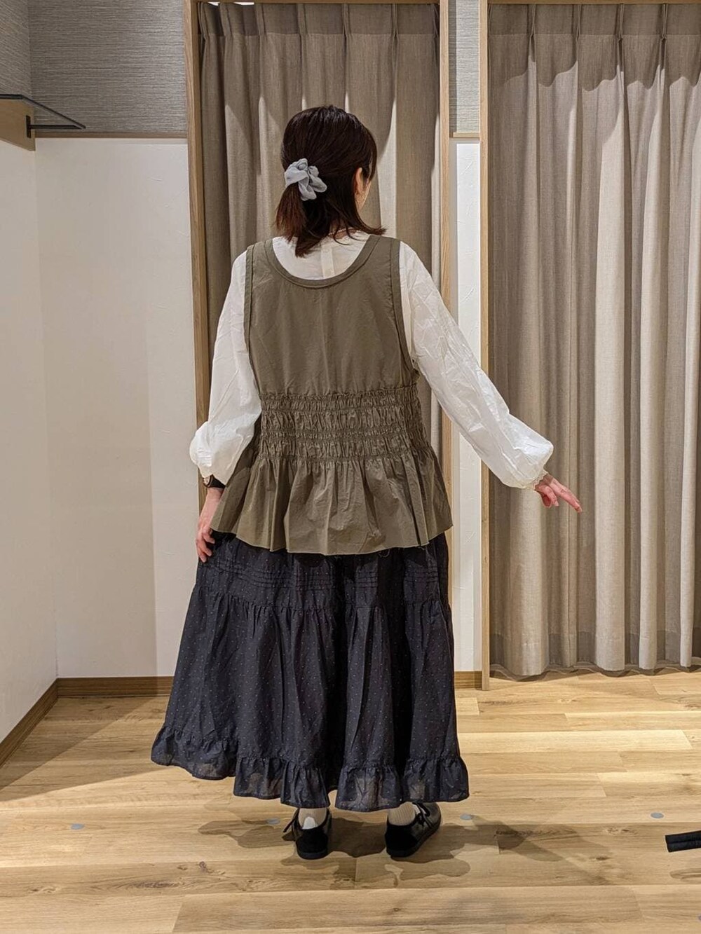 ブラック系のスニーカー、ホワイト系のシャツ/ブラウス、グリーン系のベストを着用したレディースの春コーディネートの2枚目の写真