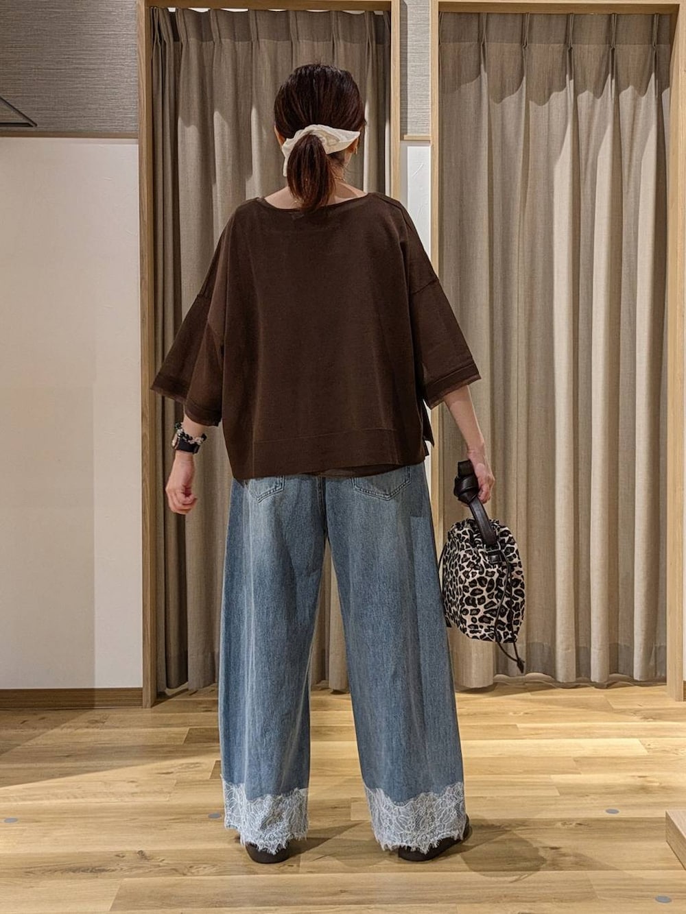 ブルー系のデニムパンツ、ベージュ系のサンダル、ブラウン系のニット/セーターを着用したレディースの夏コーディネートの3枚目の写真