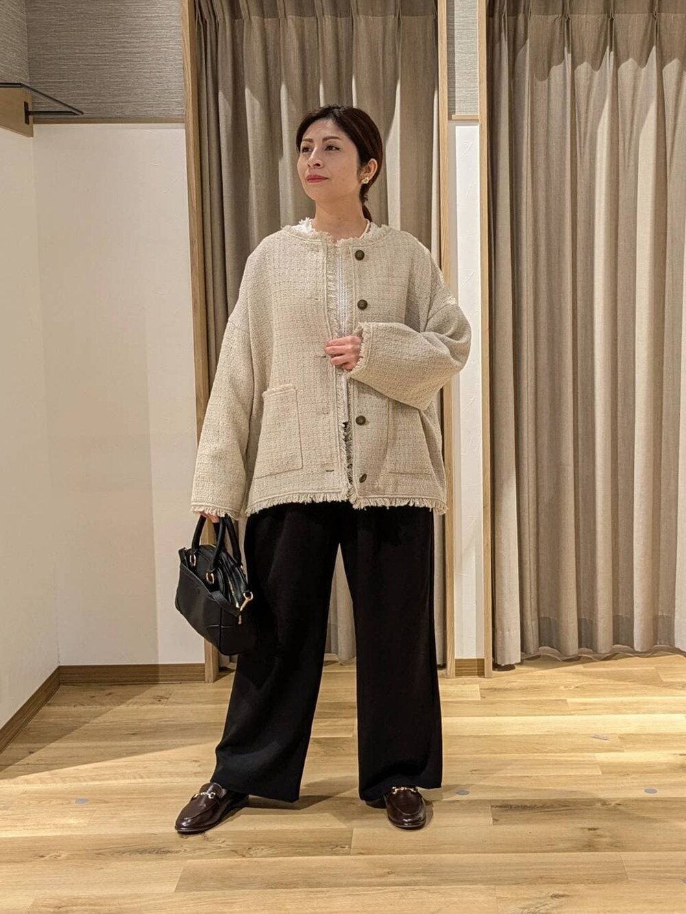 ブラック系のスラックス、ブラック系のショルダーバッグ、ベージュ系のノーカラージャケットを着用したレディースの冬コーディネートの2枚目の写真