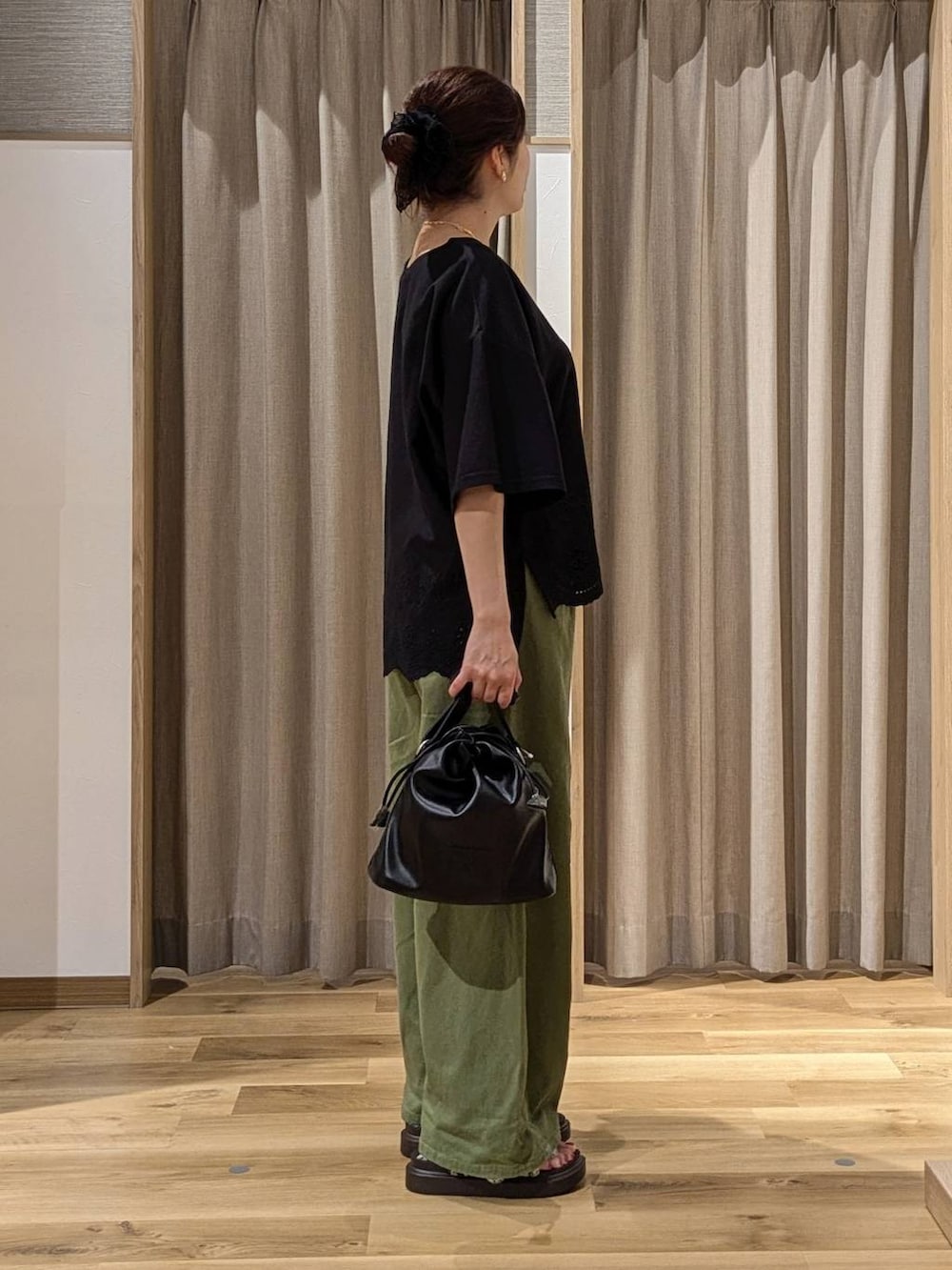 グリーン系のデニムパンツ、ブラック系のTシャツ/カットソー、ブラウン系のサンダルを着用したレディースの夏コーディネートの2枚目の写真