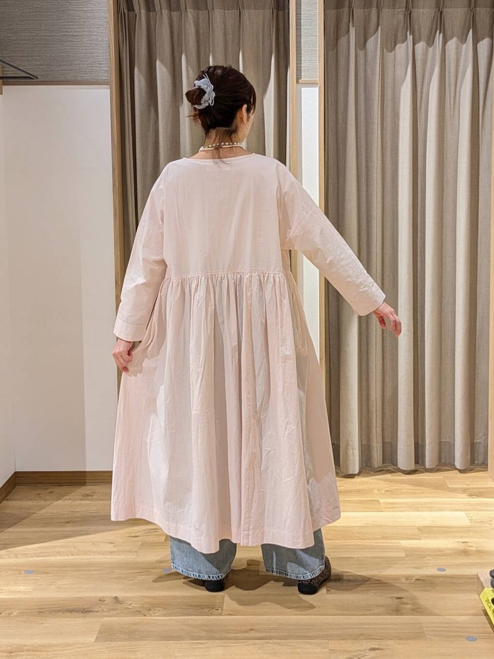 ブルー系のデニムパンツ、ベージュ系のトートバッグ、ピンク系のワンピースを着用したレディースの春コーディネートの2枚目の写真