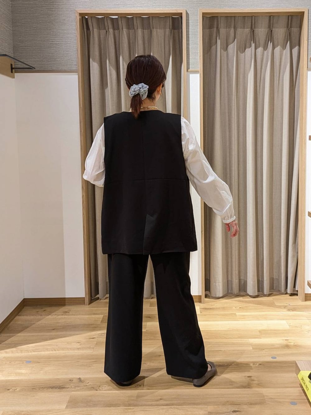 ブラック系のベスト、ブラック系のスラックス、ブラック系のトートバッグを着用したレディースの春コーディネートの2枚目の写真