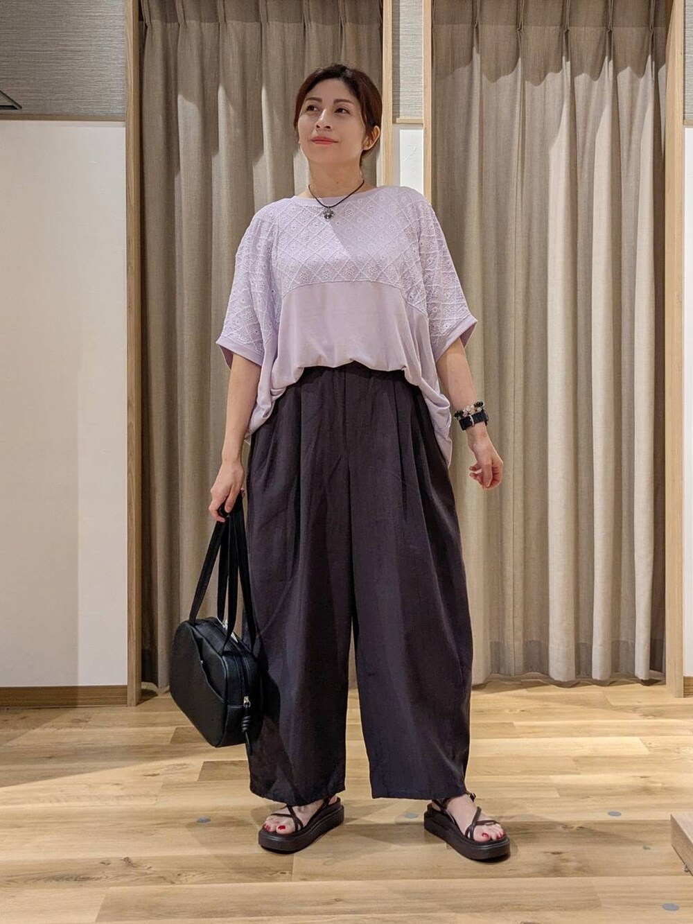 ブラック系のショルダーバッグ、パープル系のTシャツ/カットソー、ブラウン系のサンダルを着用したレディースの夏コーディネートの2枚目の写真