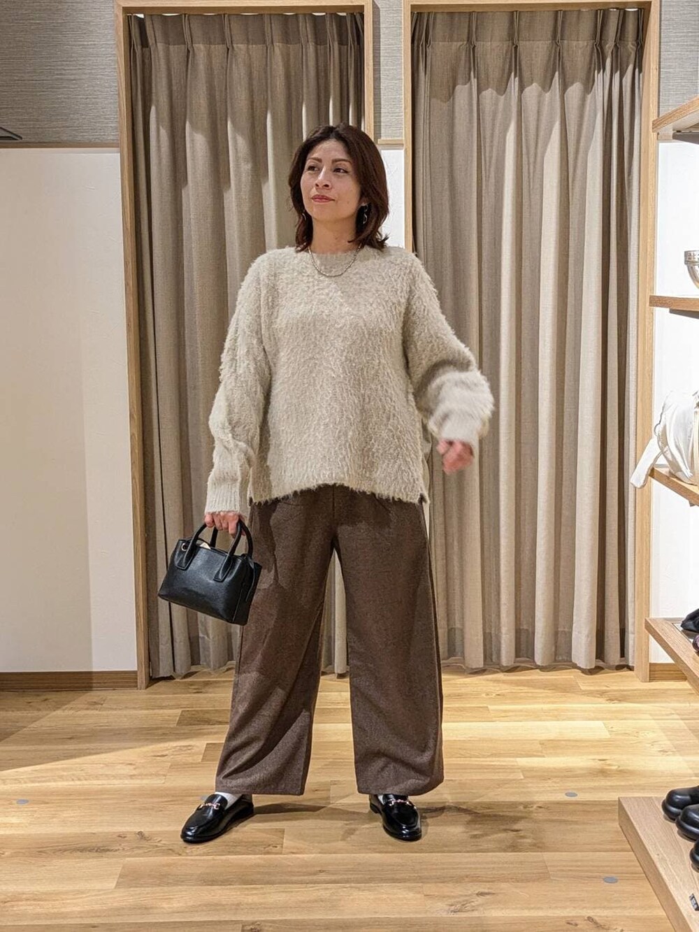 ブラウン系のその他パンツ、ベージュ系のニット/セーター、ブラック系のトートバッグを着用したレディースの冬コーディネートの2枚目の写真