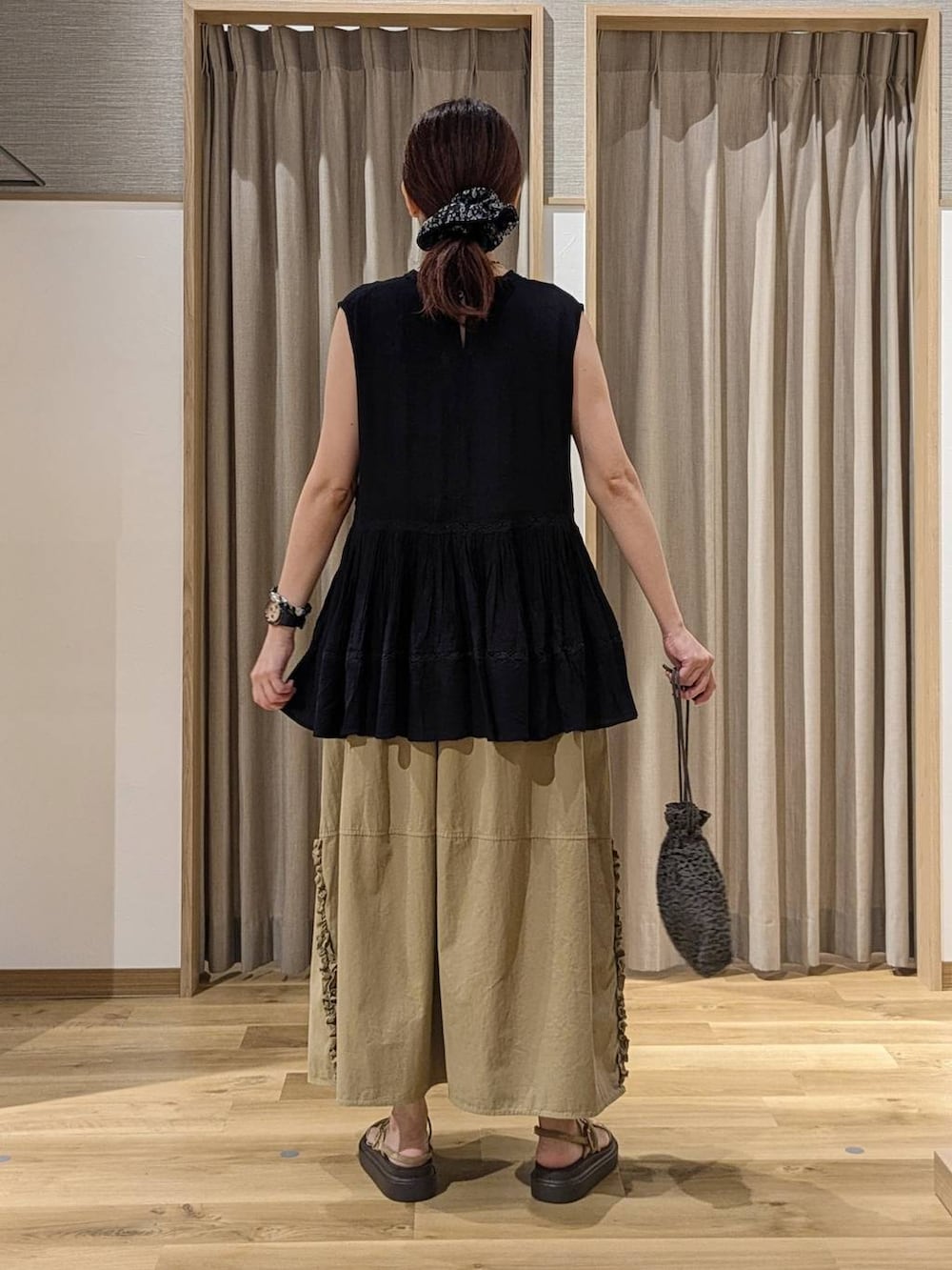 ベージュ系のスカート、ベージュ系のサンダル、ブラック系のシュシュを着用したレディースの夏コーディネートの3枚目の写真