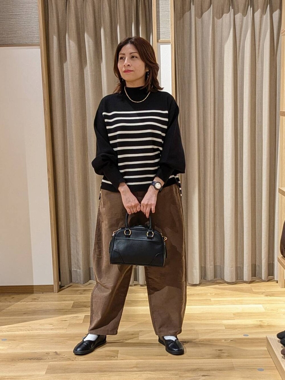 ブラウン系のその他パンツ、ブラック系のショルダーバッグ、ブラック系のスニーカーを着用したレディースの冬コーディネートの2枚目の写真
