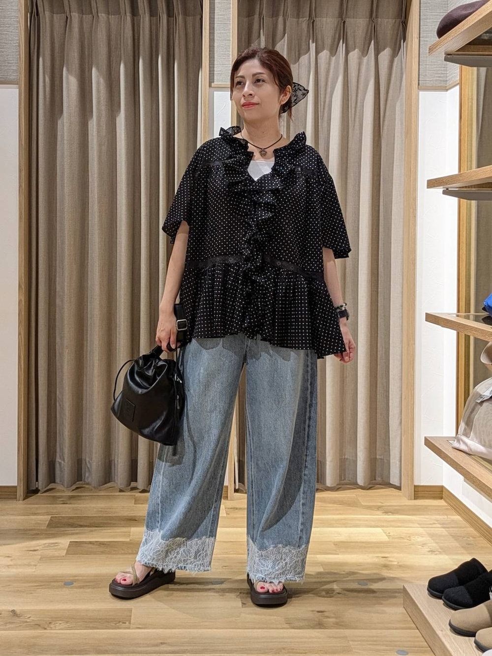 ブルー系のデニムパンツ、ベージュ系のサンダル、ブラック系のトートバッグを着用したレディースの夏コーディネートの2枚目の写真