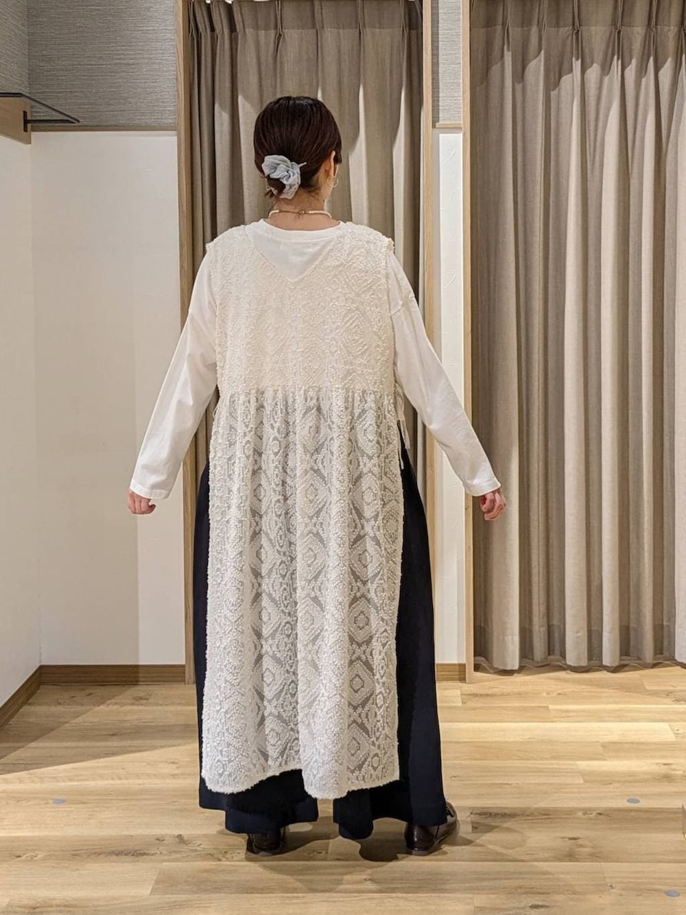 グリーン系のトートバッグ、ブラウン系のローファー、ホワイト系のベストを着用したレディースの冬コーディネートの2枚目の写真