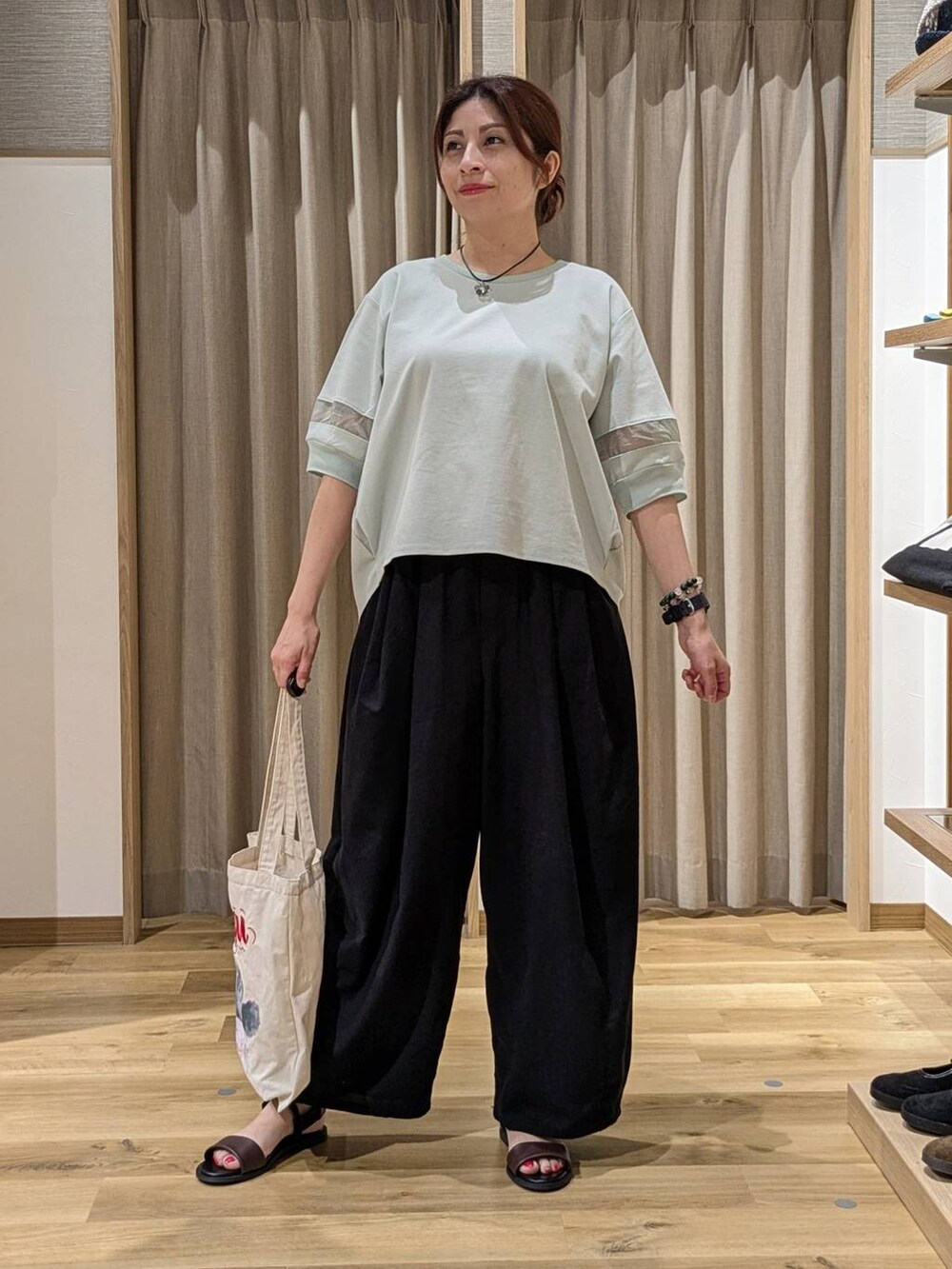 グリーン系のTシャツ/カットソー、ブラック系のその他パンツ、ブラウン系のサンダルを着用したレディースの夏コーディネートの2枚目の写真