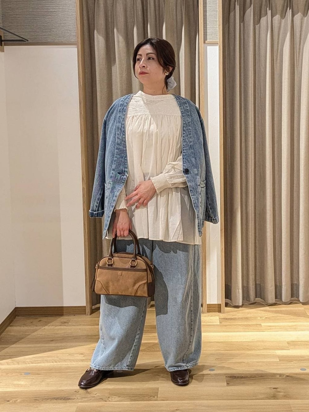 ブルー系のデニムパンツ、ブラウン系のショルダーバッグ、ホワイト系のシャツ/ブラウスを着用したレディースの冬コーディネートの2枚目の写真