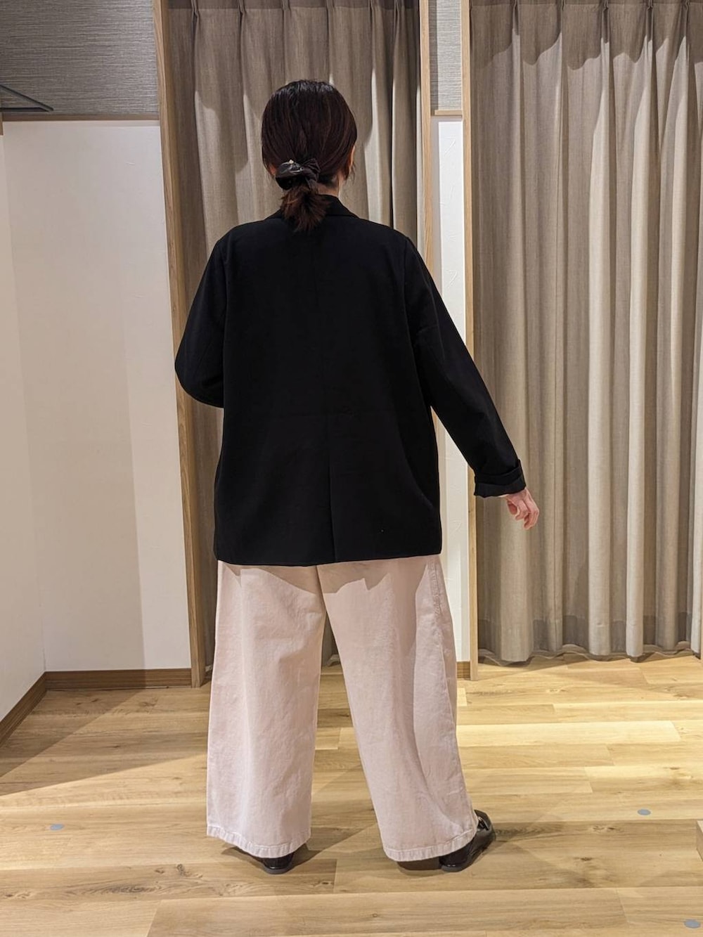 ブラック系のテーラードジャケット、ブラウン系のショルダーバッグ、ピンク系のチノパンツを着用したレディースの冬コーディネートの2枚目の写真