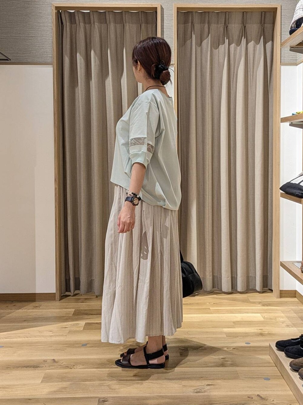 ブラック系のショルダーバッグ、グリーン系のTシャツ/カットソー、その他のスカートを着用したレディースの夏コーディネートの2枚目の写真