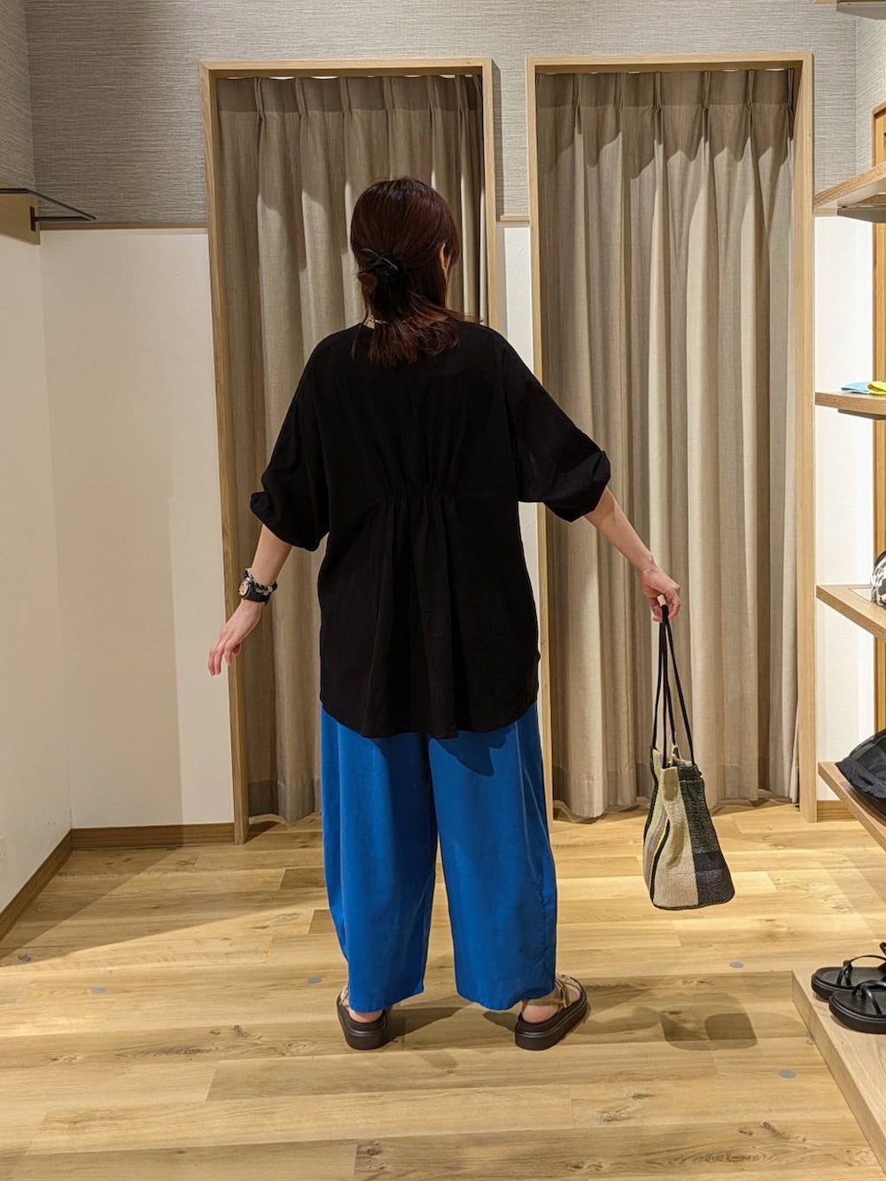 ブラック系のトートバッグ、ベージュ系のサンダル、ブラック系のタンクトップを着用したレディースの夏コーディネートの2枚目の写真