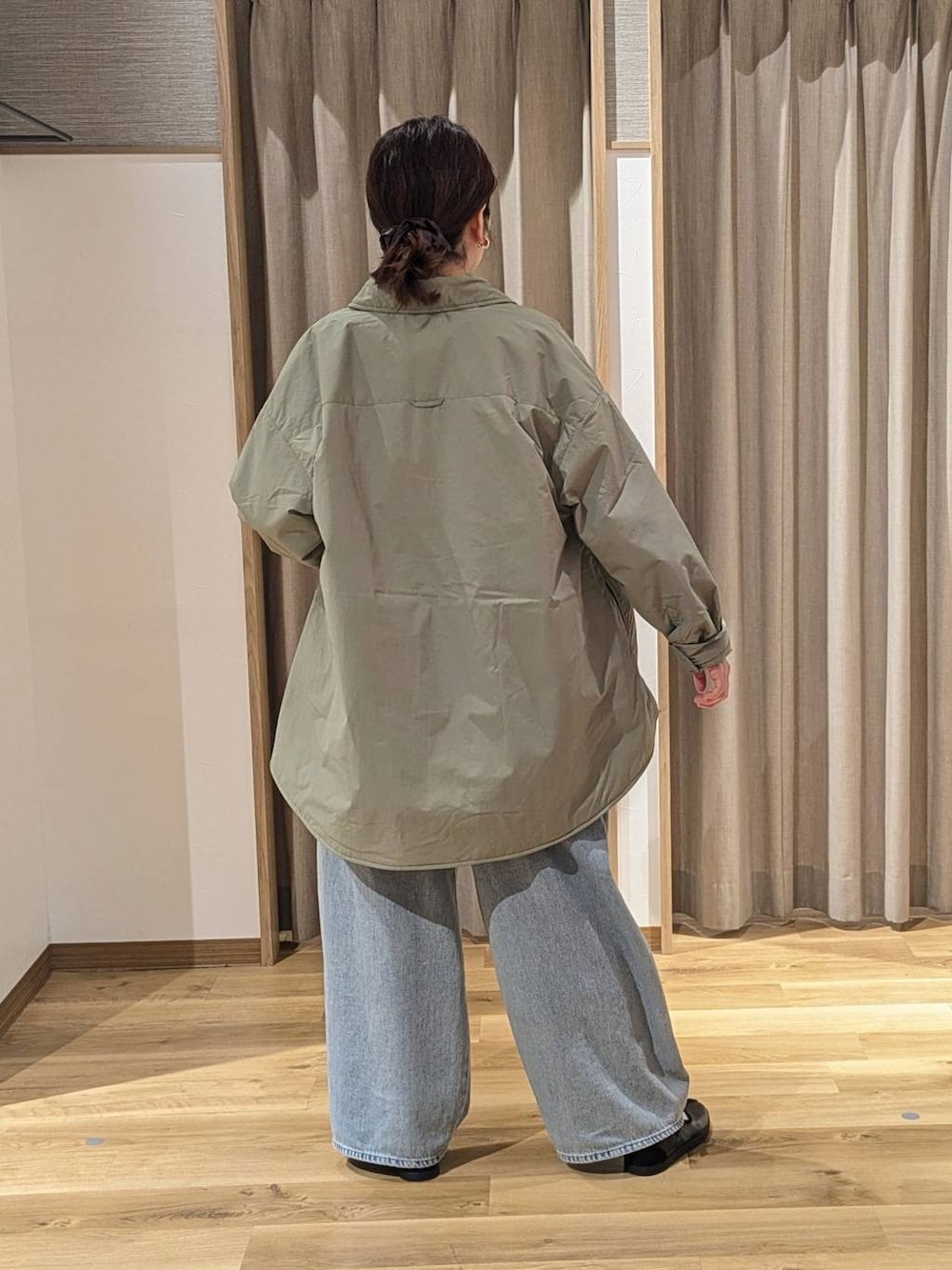 グリーン系のその他アウター、ブルー系のデニムパンツ、ブラック系のスニーカーを着用したレディースの冬コーディネートの2枚目の写真