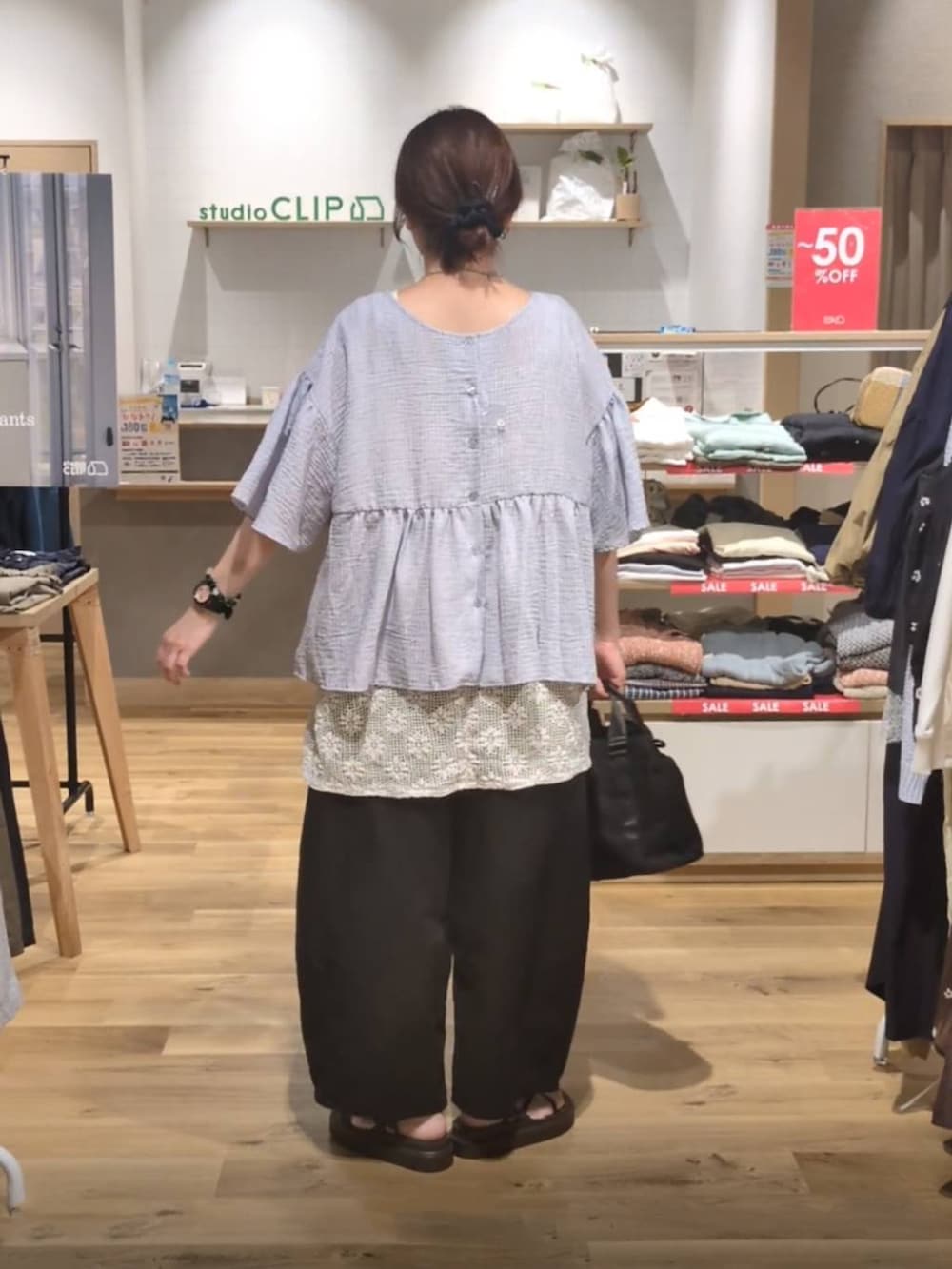ブラウン系のサンダル、ホワイト系のベスト、ブラック系のその他パンツを着用したレディースの夏コーディネートの2枚目の写真