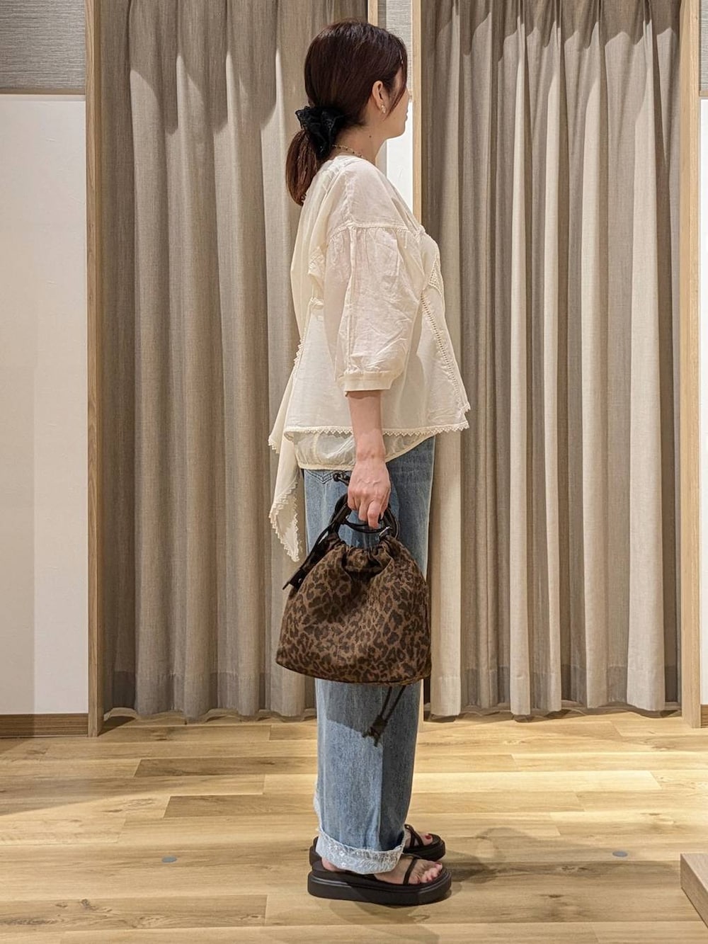 ブルー系のデニムパンツ、ベージュ系のキャミソール、ホワイト系のシャツ/ブラウスを着用したレディースの夏コーディネートの2枚目の写真