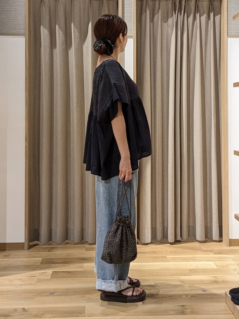 ブルー系のデニムパンツ、ブラウン系のサンダル、ブラック系のシャツ/ブラウスを着用したレディースの夏コーディネートの2枚目の写真