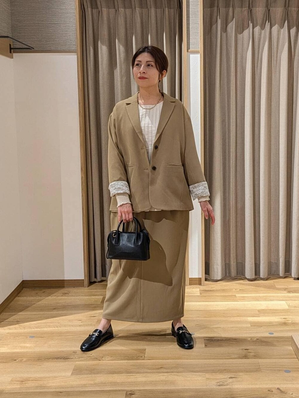 ベージュ系のスカート、ベージュ系のテーラードジャケット、ブラック系のトートバッグを着用したレディースの冬コーディネートの2枚目の写真
