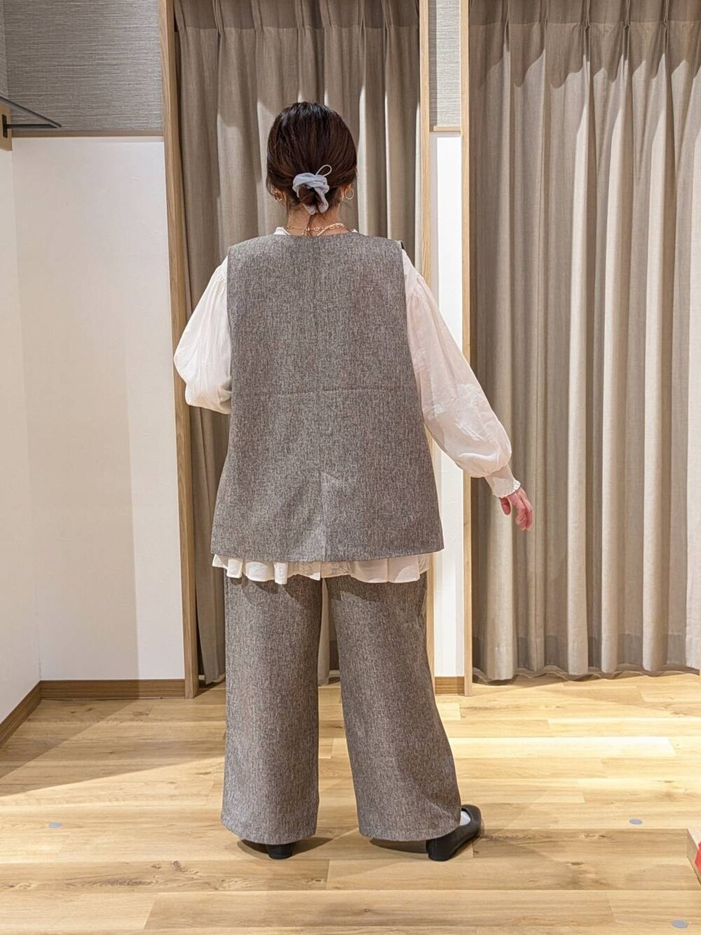 ベージュ系のベスト、ベージュ系のスラックス、ブラック系のショルダーバッグを着用したレディースの冬コーディネートの2枚目の写真