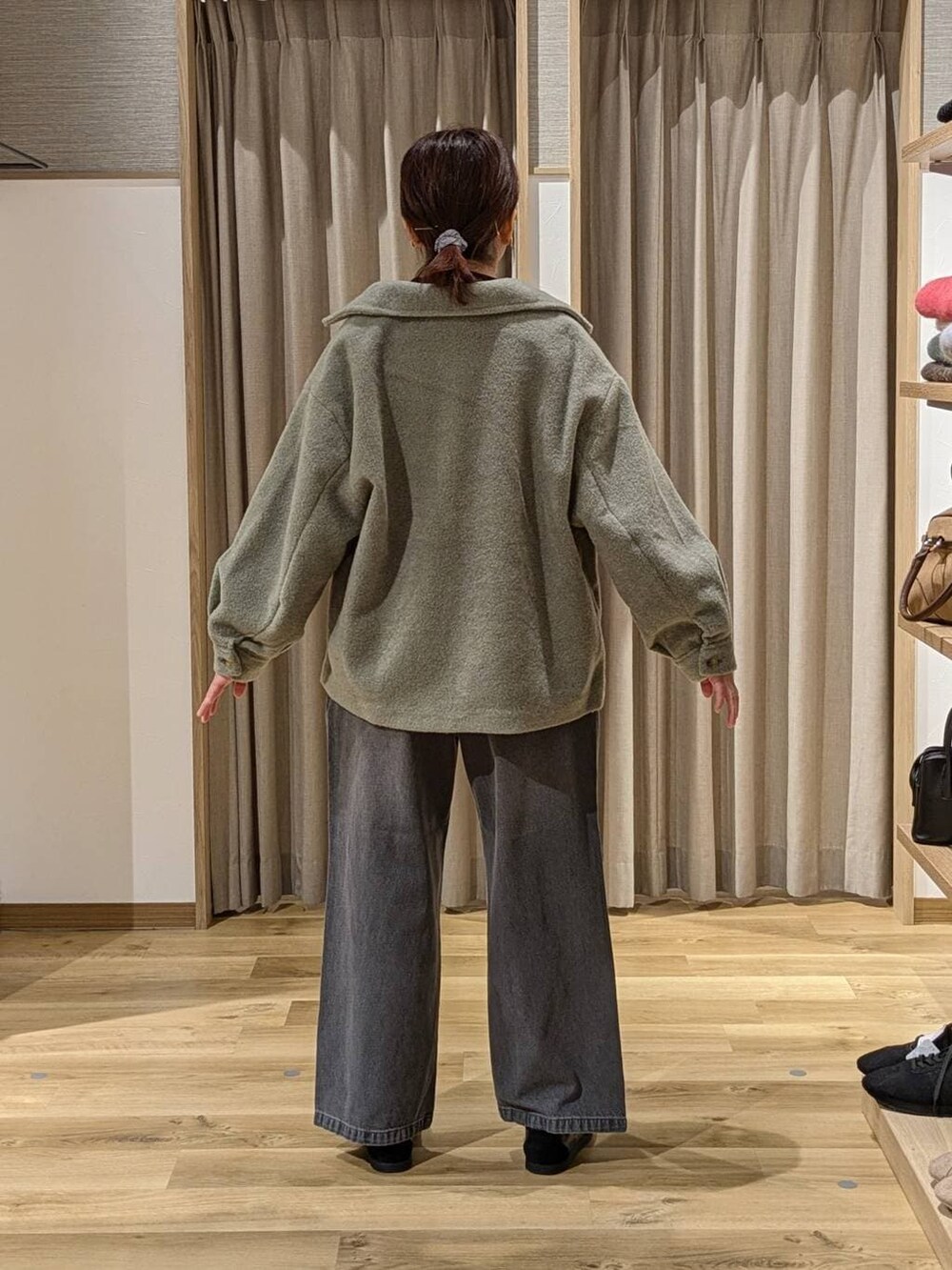 グリーン系のブルゾン、グレー系のデニムパンツ、ブラック系のショルダーバッグを着用したレディースの冬コーディネートの3枚目の写真