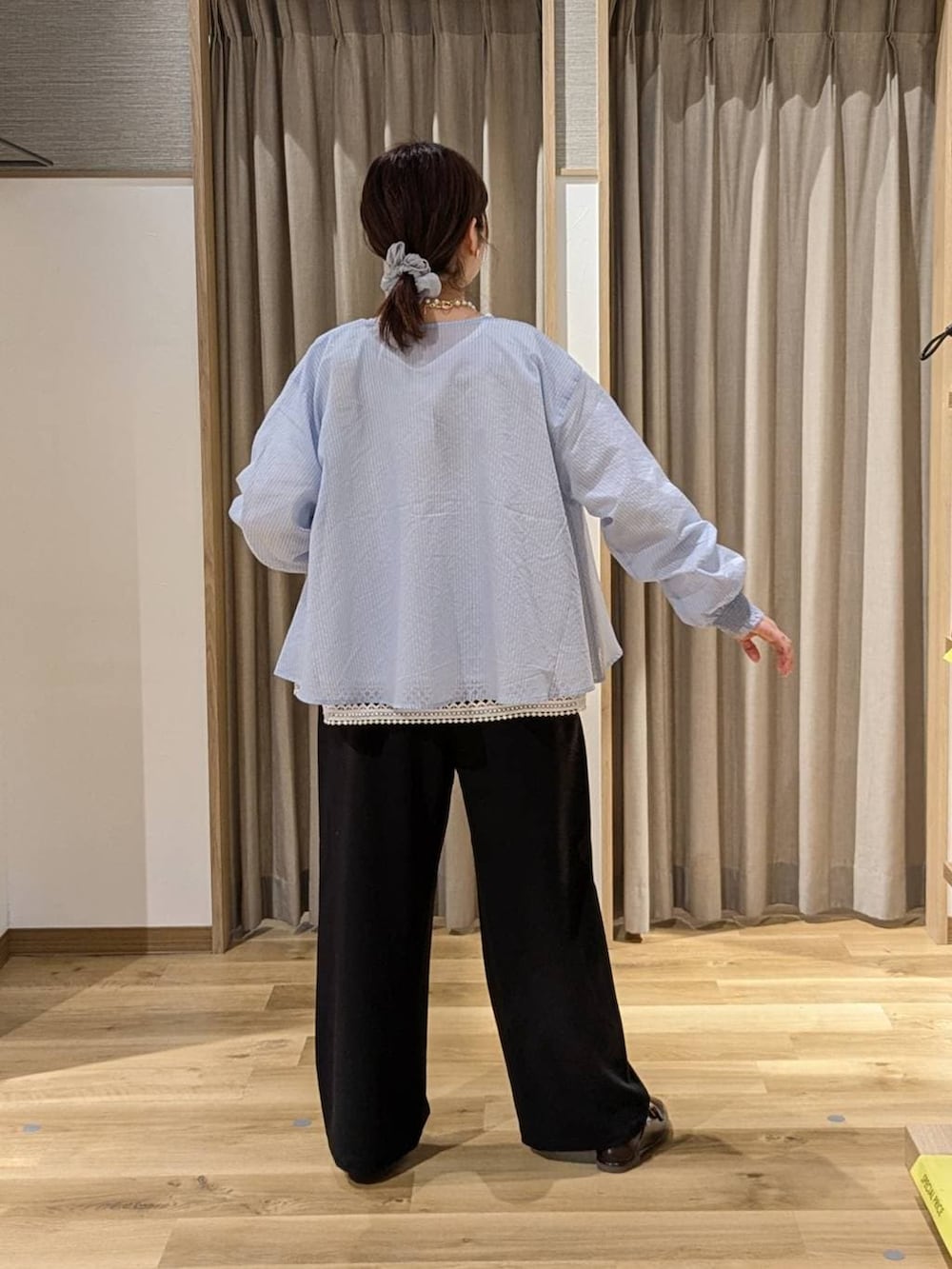 ブラック系のスラックス、ブラック系のトートバッグ、ブラウン系のローファーを着用したレディースの春コーディネートの2枚目の写真