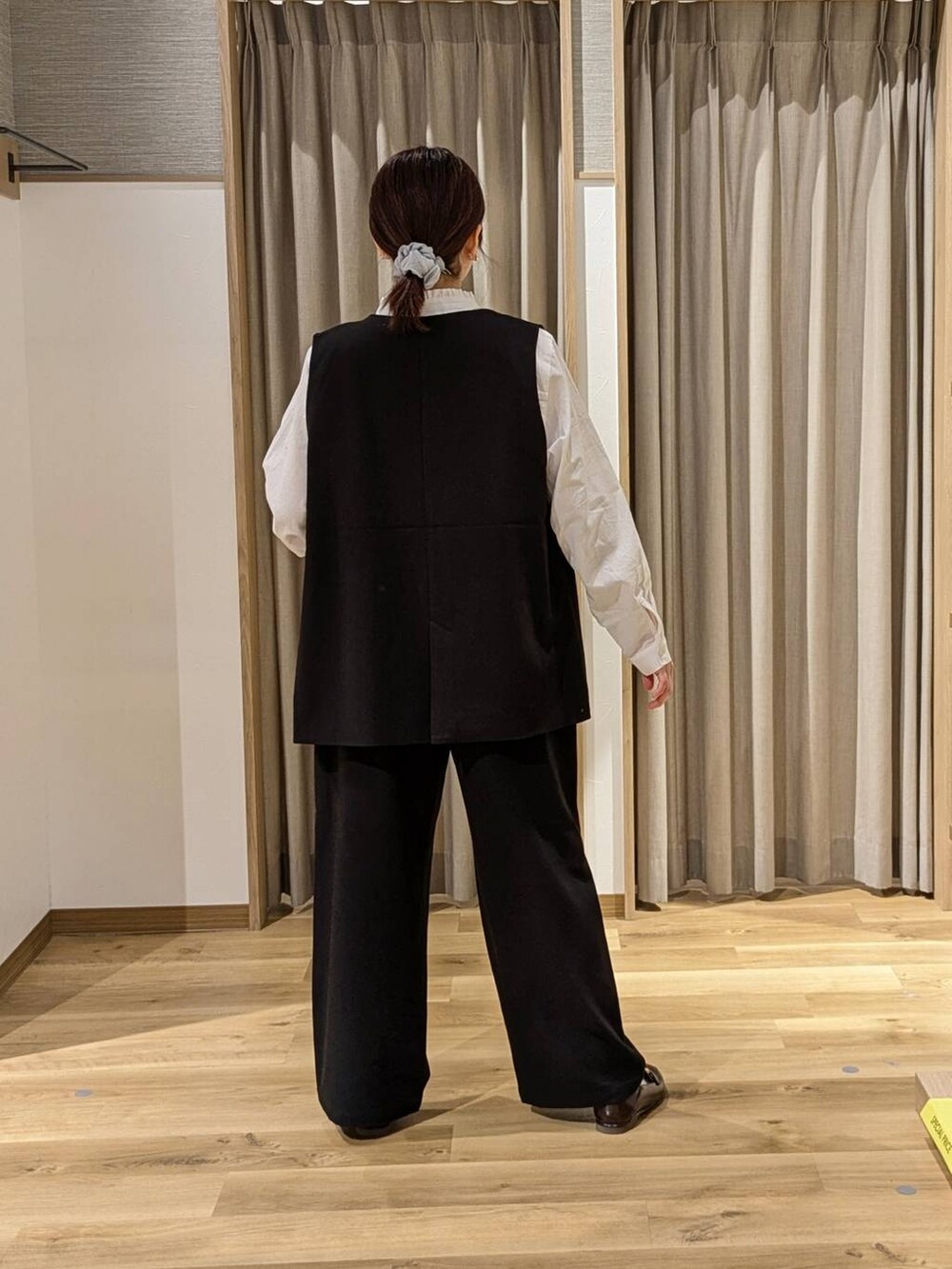 ブラック系のベスト、ブラック系のスラックス、ブラウン系のトートバッグを着用したレディースの冬コーディネートの2枚目の写真