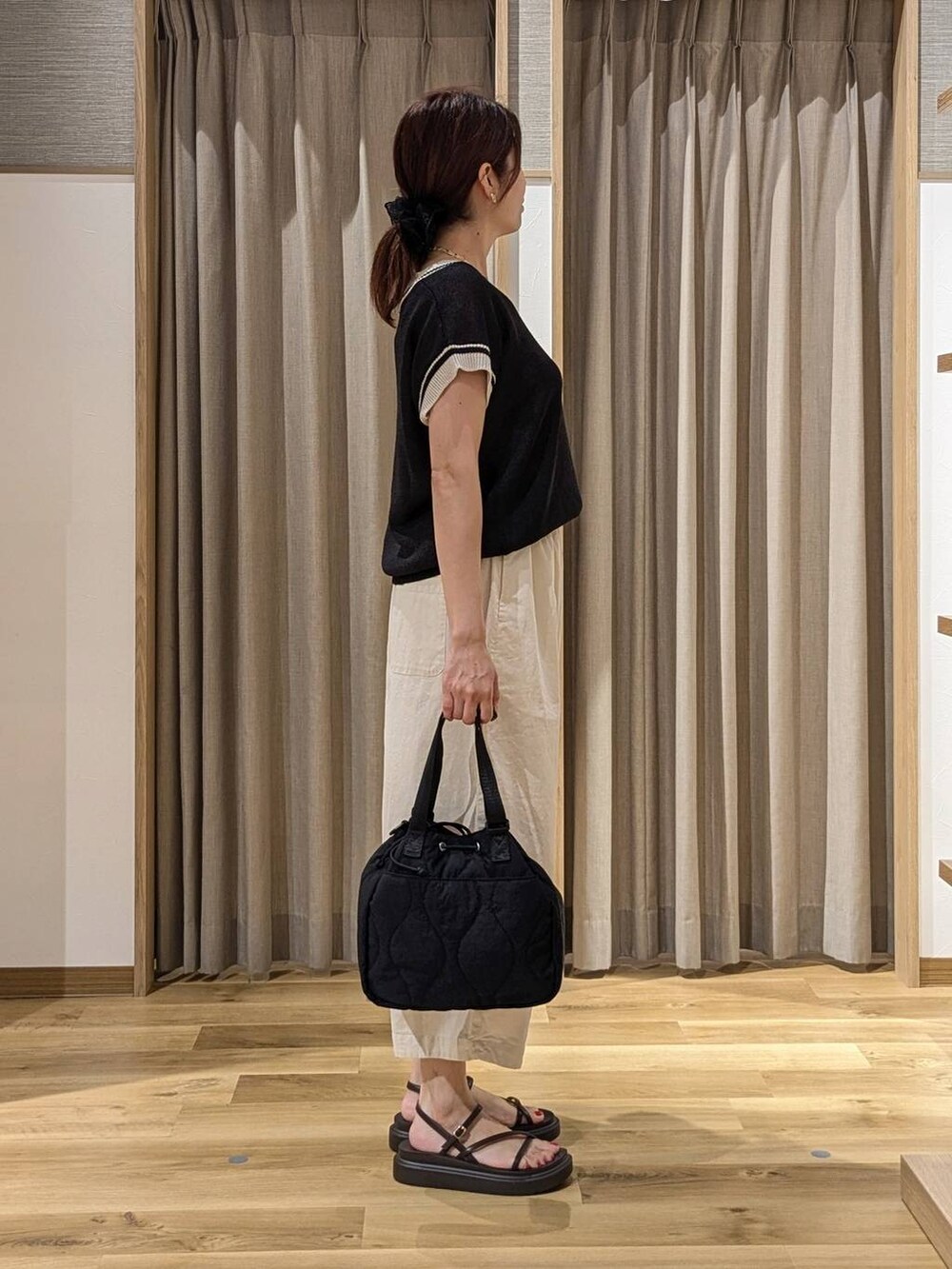 ブラック系のニット/セーター、ブラウン系のサンダル、ホワイト系のその他パンツを着用したレディースの夏コーディネートの2枚目の写真