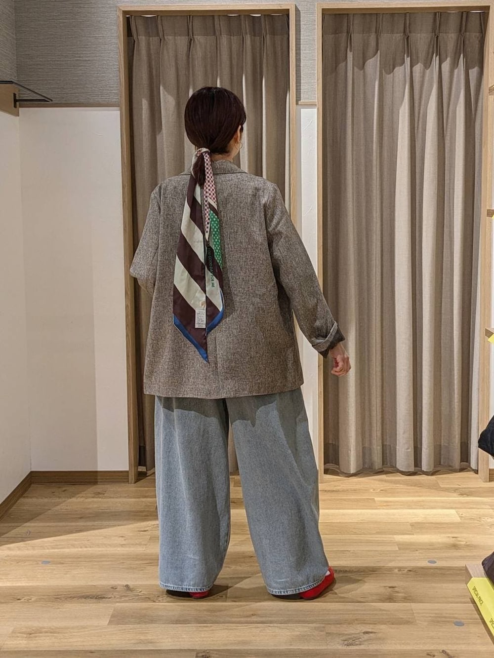 ベージュ系のテーラードジャケット、レッド系のパンプス、ブルー系のデニムパンツを着用したレディースの冬コーディネートの2枚目の写真