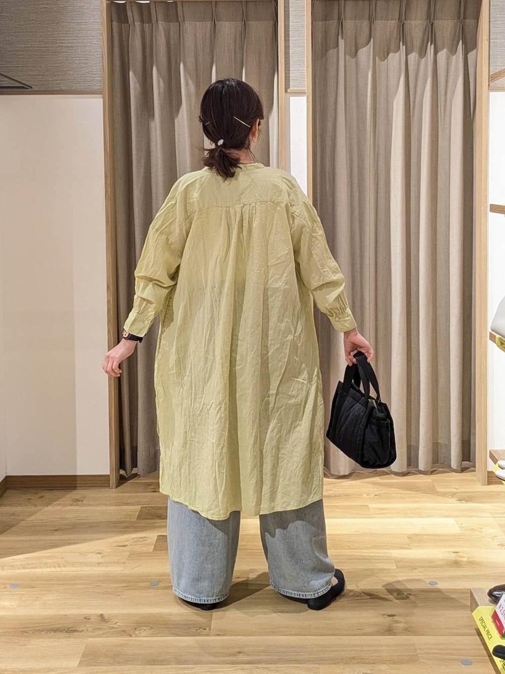 ブルー系のデニムパンツ、ブラック系のトートバッグ、ホワイト系のタンクトップを着用したレディースの春コーディネートの2枚目の写真