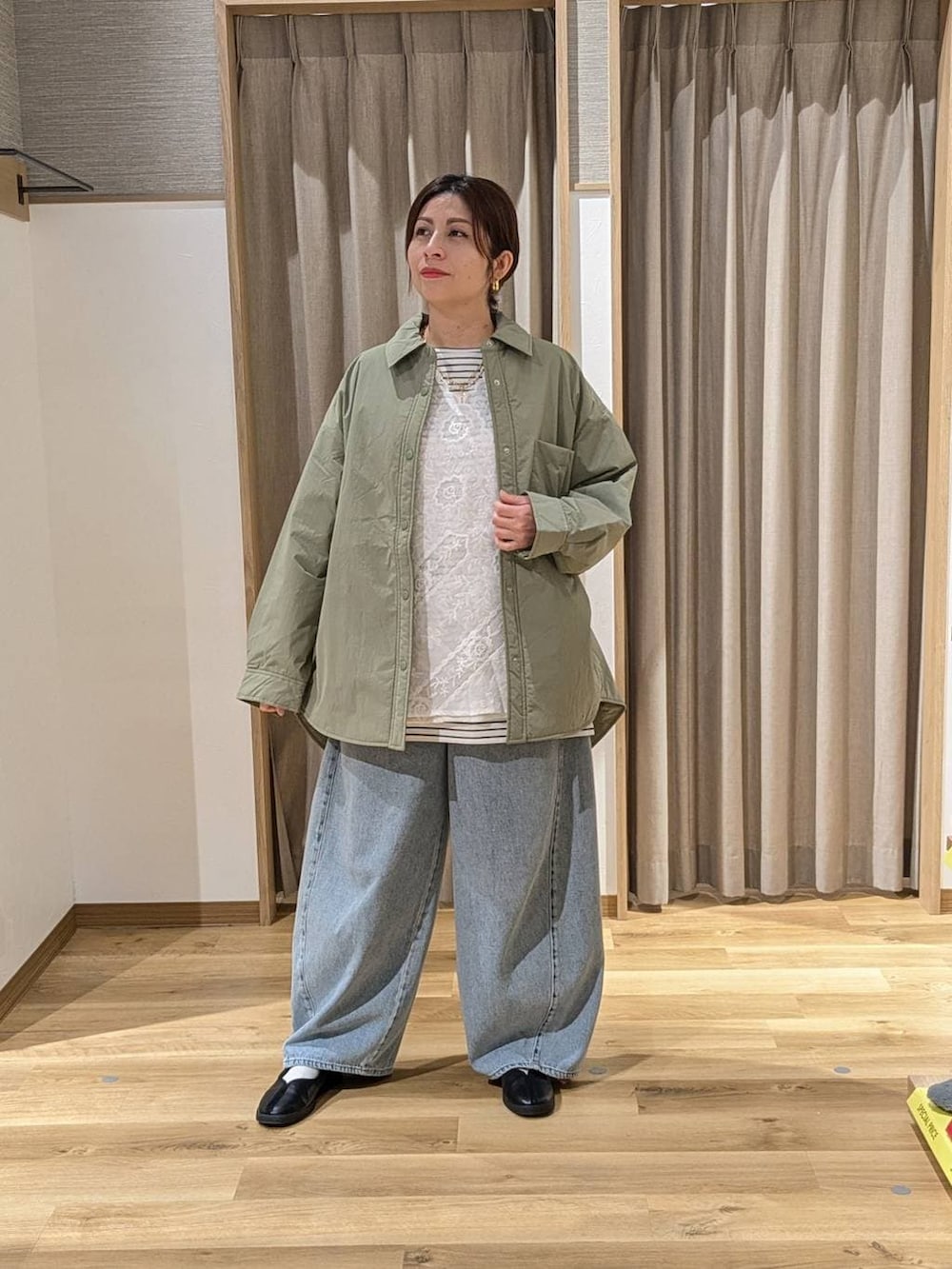 グリーン系のその他アウター、ブラック系のスニーカー、ブルー系のデニムパンツを着用したレディースの冬コーディネートの2枚目の写真